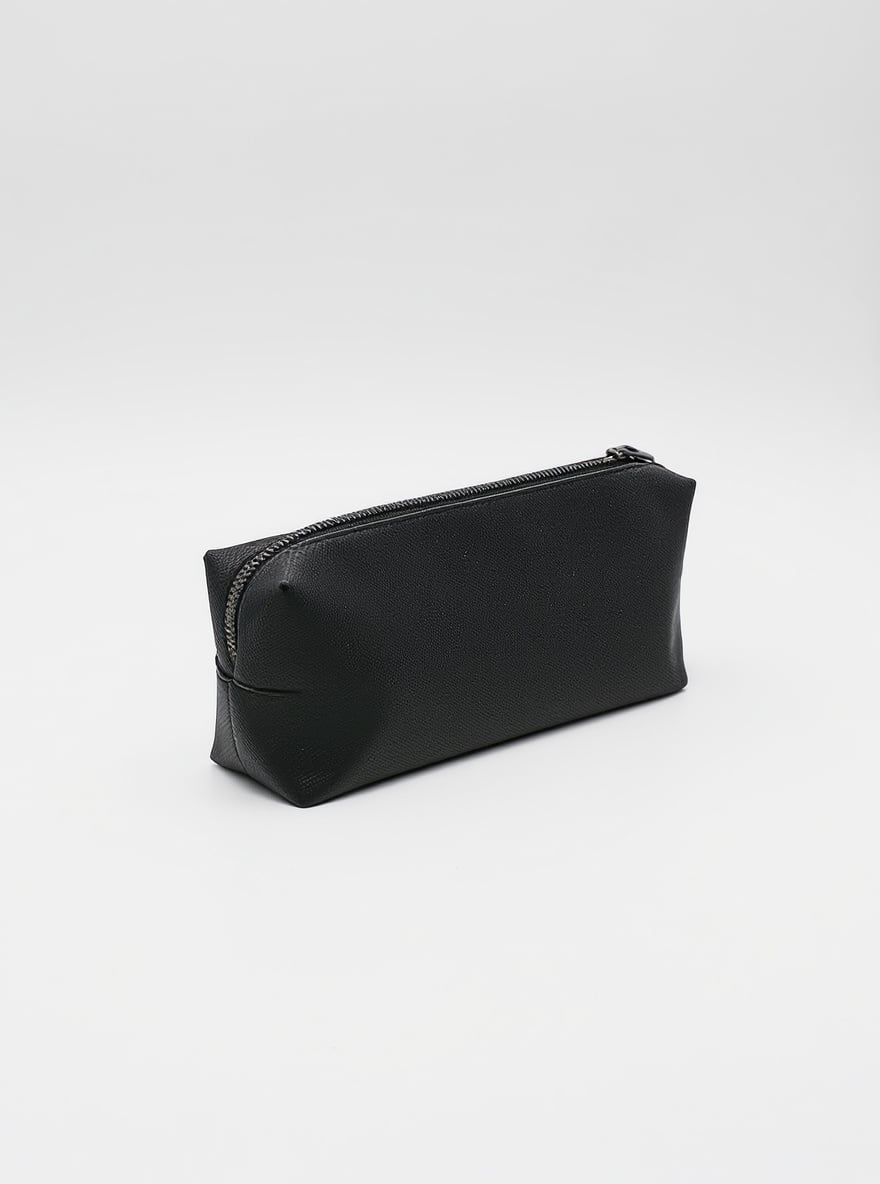 The Ink Pencil Pouch on a plain backdrop: slim ink-black coated cotton with a flat base and matte zip.
