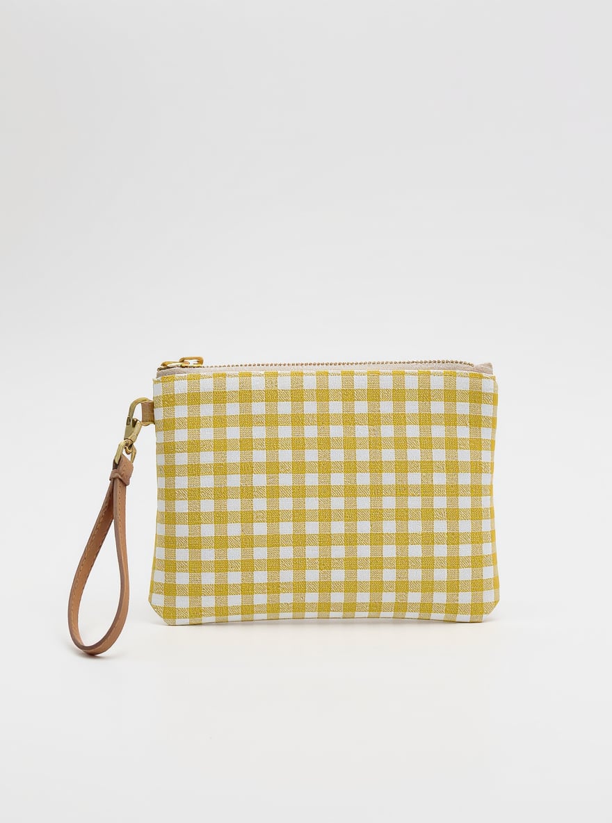 The Lemon Wristlet on a plain backdrop: yellow ticking-stripe cotton with a brass D-ring and leather wrist strap.