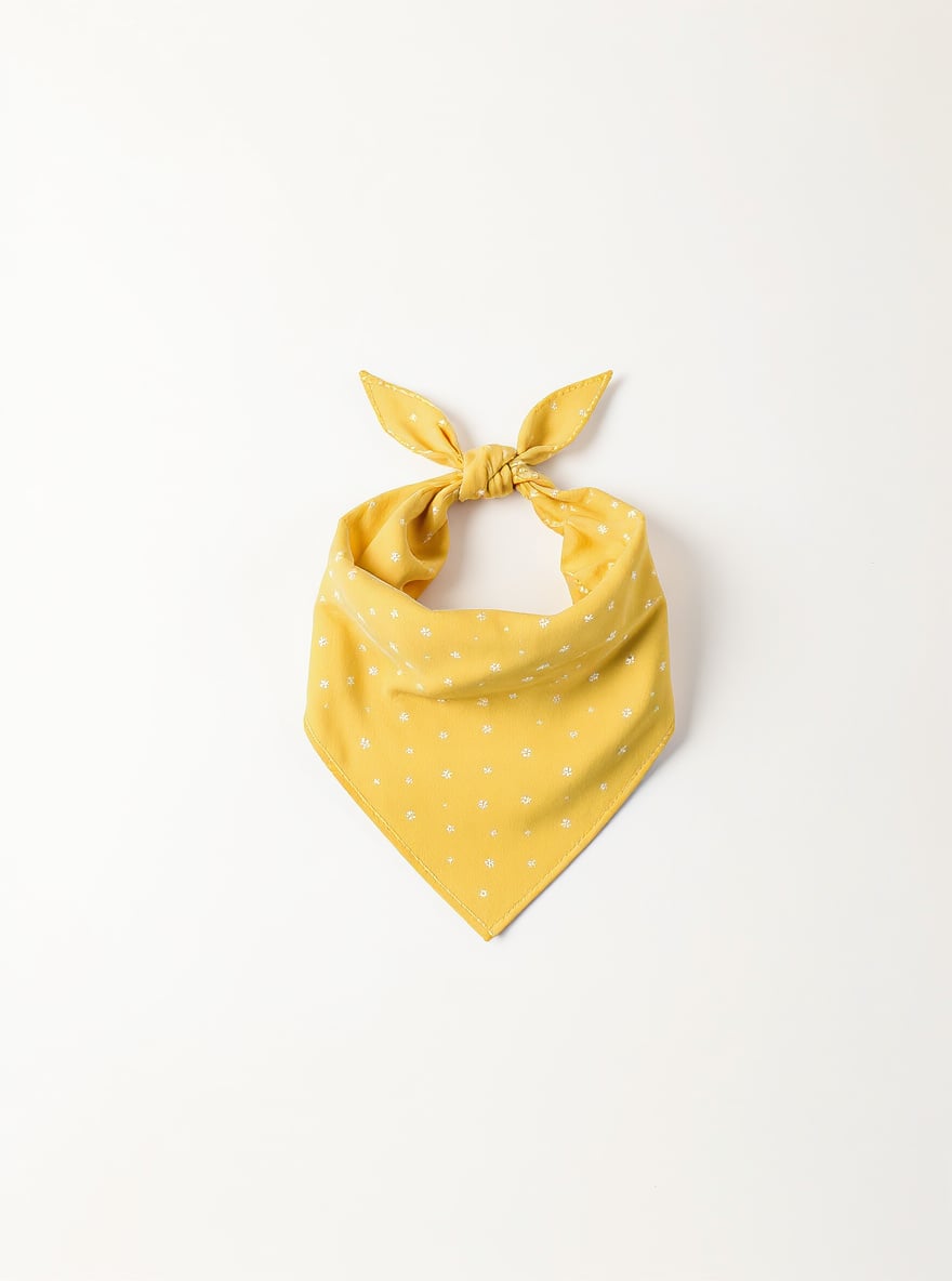 The Sunny Day Dog Bandana folded flat: yellow washed cotton with a ditsy floral print.